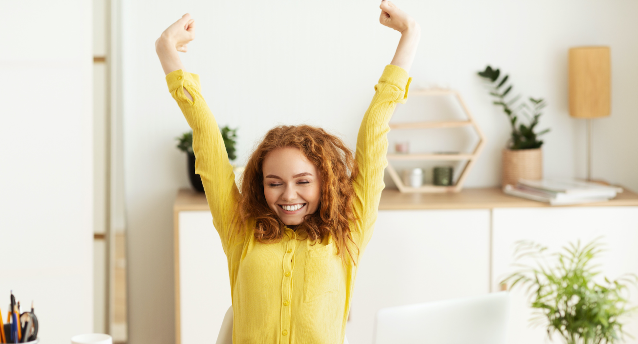 Woman in yellow sweater stretching while working from home