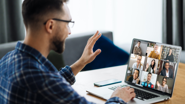 Man waving at a computer while on a video conference call