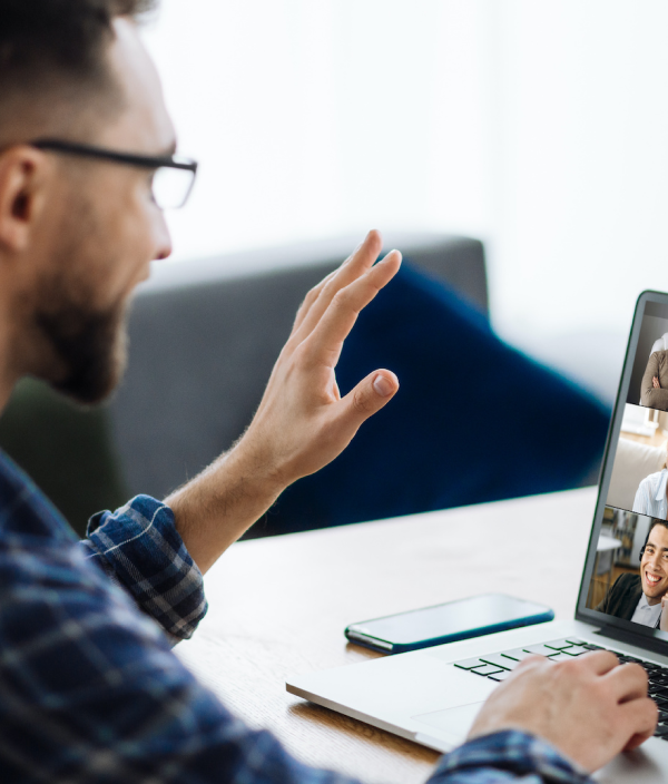 Man waving at a computer while on a video conference call