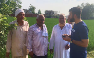 A young man talks with three older men outside.