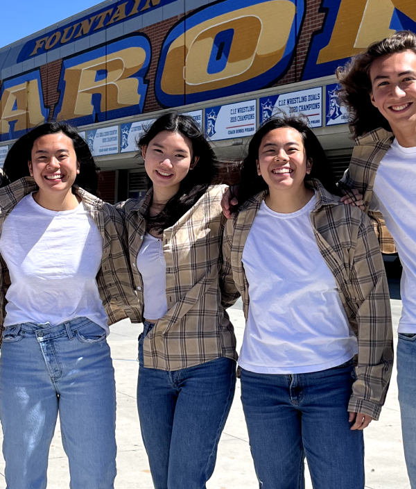 Five high schoolers of various ethnicities pose in tan flannels and white t-shirts.