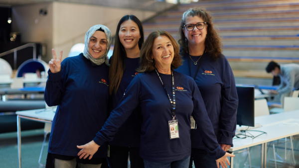 Four engineers pose for a photo at the Intuit campus wearing dark blue shirts with the GED logo.