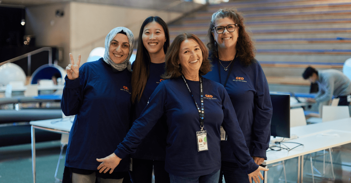 Four engineers pose for a photo at the Intuit campus wearing dark blue shirts with the GED logo.