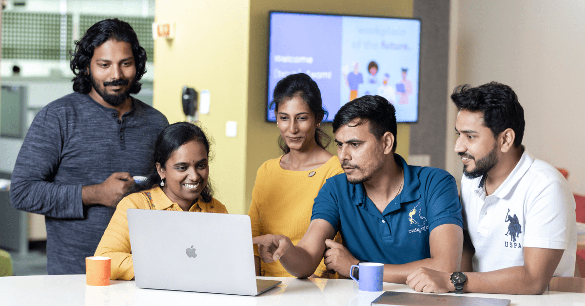 Five Indian tech professionals collaborate on a project around a computer.