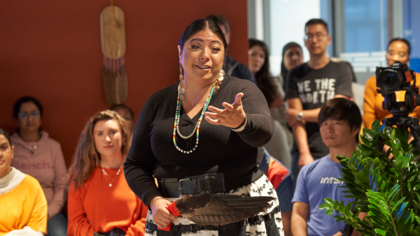 An Indigenous woman performs a blessing ceremony to employees in an office.