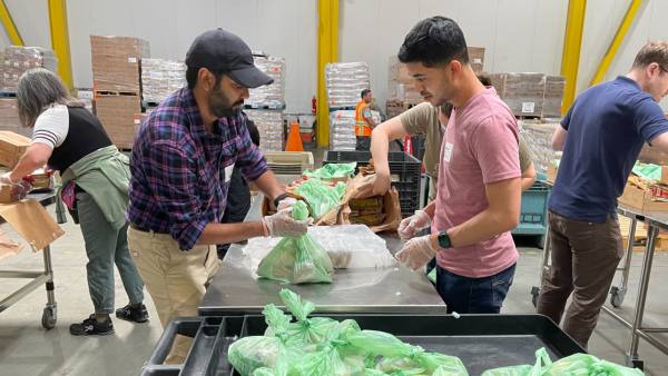 Two men volunteers package boxes with sustainable goods and materials.