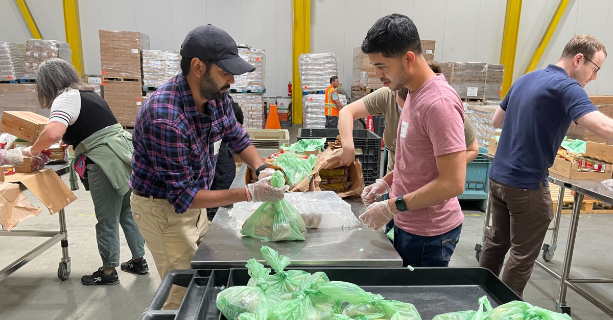 Two men volunteers package boxes with sustainable goods and materials.