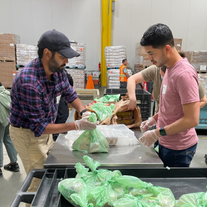 Two men volunteers package boxes with sustainable goods and materials.