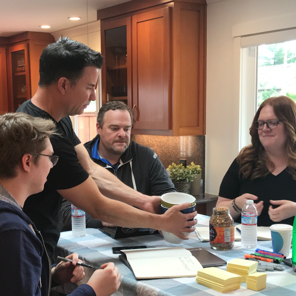 Volunteer handing bowl to group of three people gathered around a table