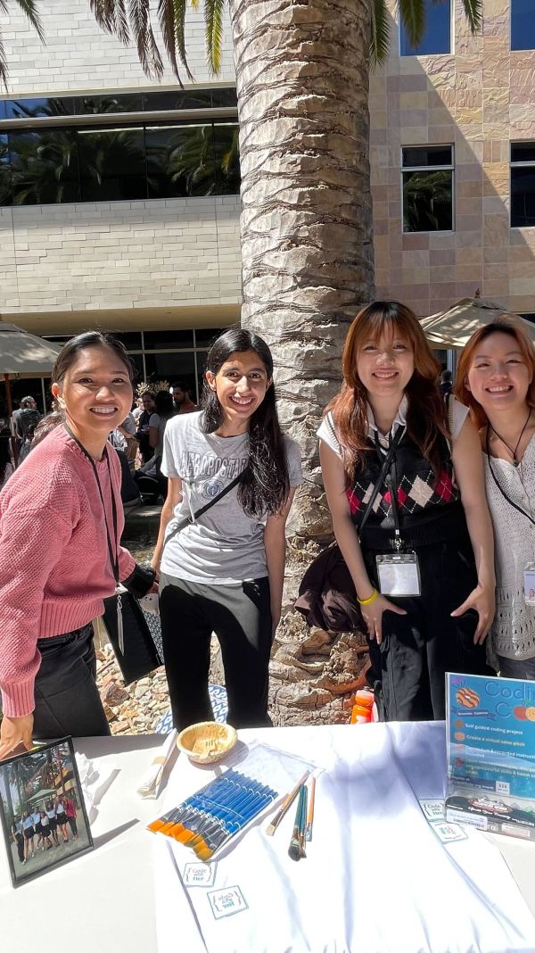 Four women standing behind 'Coding for Kids' booth