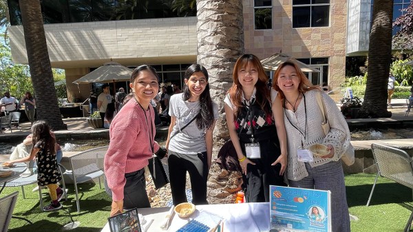 Four women standing behind 'Coding for Kids' booth