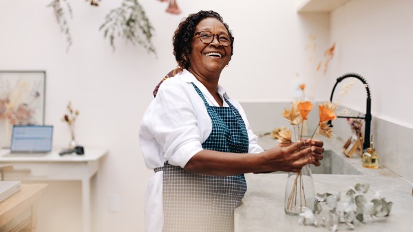 A Black, female business owner poses in her luxury floral shop.