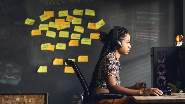 Woman working in front of her desk, behind her a collage of sticky notes