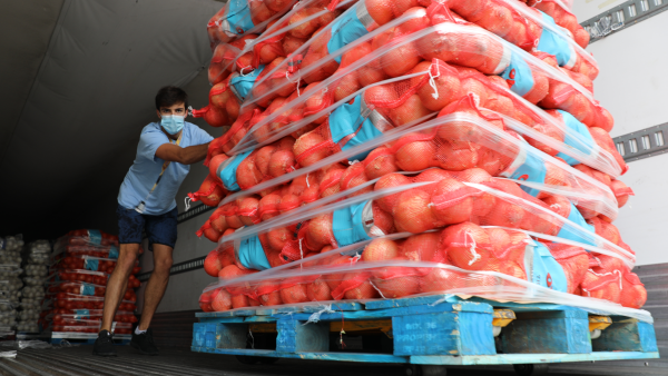 Man with mask pushing cartons of food out of a truck